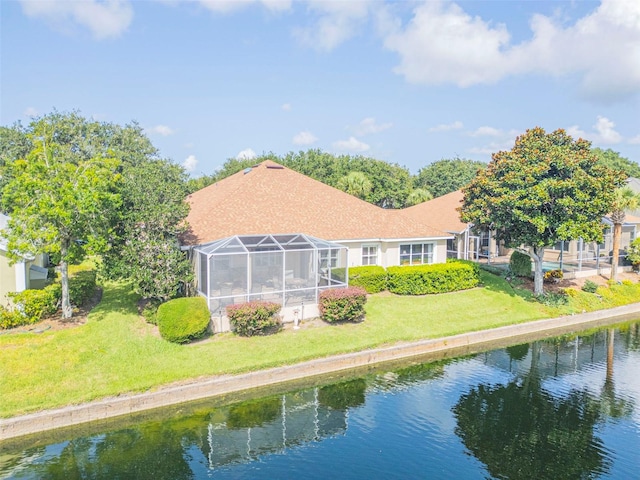 back of property with a yard, a lanai, and a water view