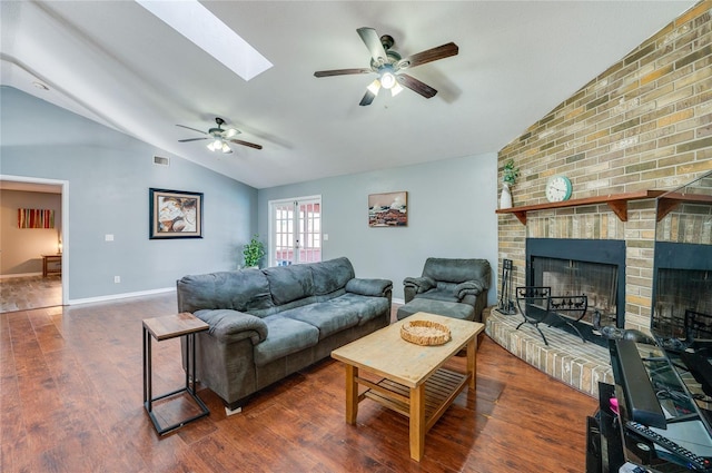 living room with a fireplace, lofted ceiling with skylight, dark hardwood / wood-style floors, and ceiling fan