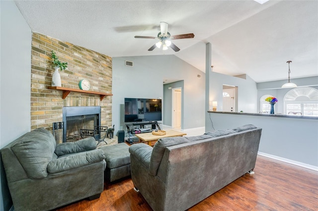 living room featuring vaulted ceiling, dark wood-type flooring, ceiling fan, and a fireplace