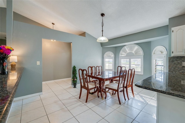 dining area featuring vaulted ceiling, light tile patterned floors, and a textured ceiling