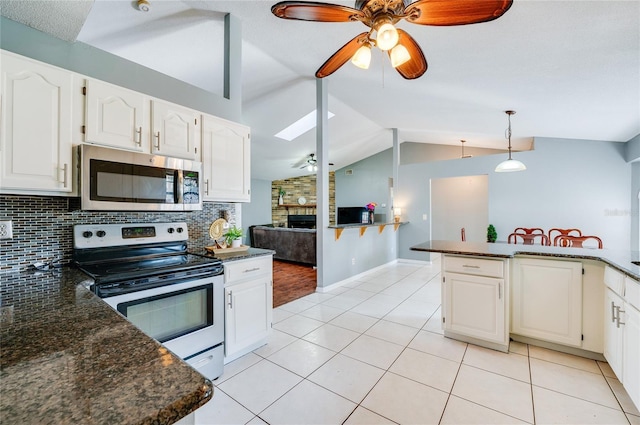 kitchen with lofted ceiling with skylight, appliances with stainless steel finishes, white cabinets, light tile patterned floors, and ceiling fan