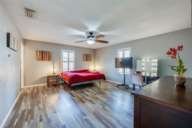 bedroom with hardwood / wood-style floors, a textured ceiling, and ceiling fan