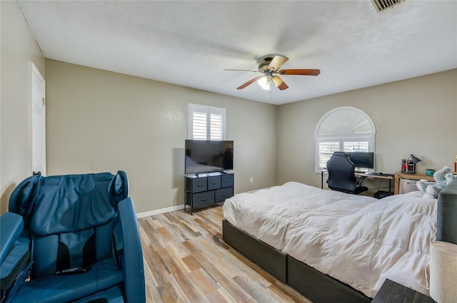 bedroom with ceiling fan, light hardwood / wood-style floors, and a textured ceiling