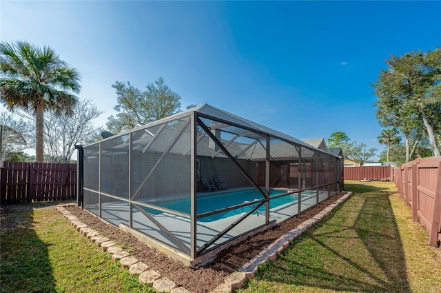 view of pool with a lawn and glass enclosure