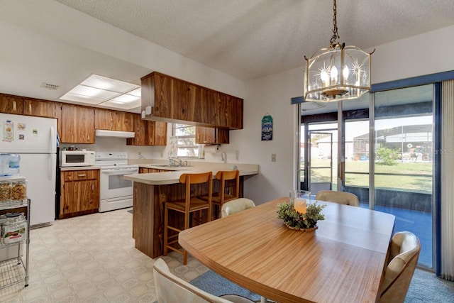 dining space featuring sink, a notable chandelier, and a textured ceiling