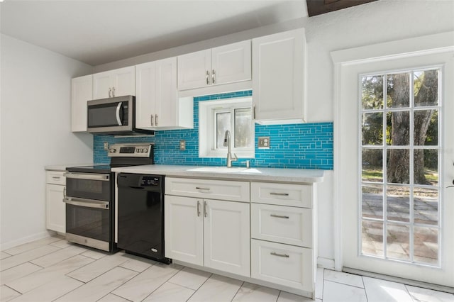 kitchen featuring tasteful backsplash, white cabinetry, appliances with stainless steel finishes, and sink