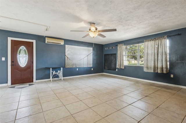 tiled foyer entrance with a textured ceiling, a wall unit AC, and ceiling fan