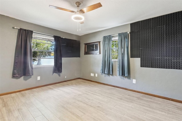 empty room with ceiling fan, light hardwood / wood-style flooring, and a healthy amount of sunlight