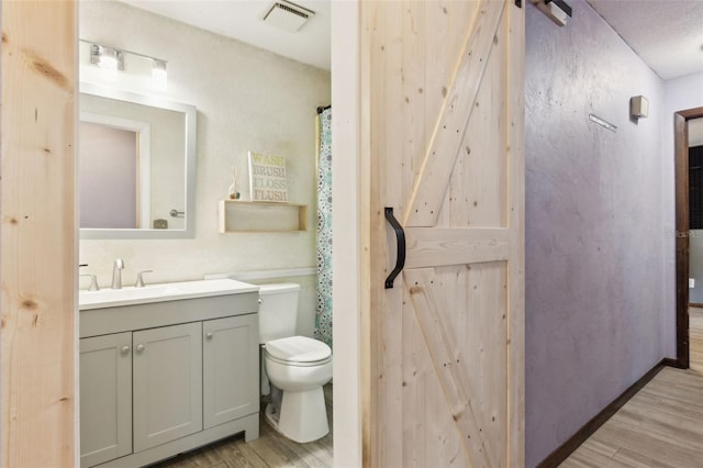 bathroom with hardwood / wood-style flooring, vanity, toilet, and a textured ceiling