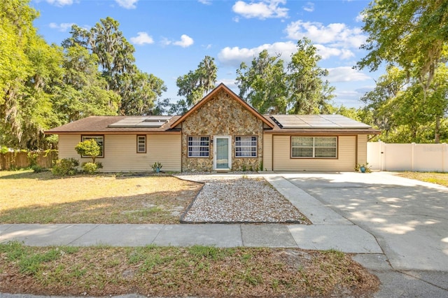 1240 W Voorhis Ave, Deland, FL 32720 - single story home featuring roof mounted solar panels, fence, concrete driveway, and stone siding