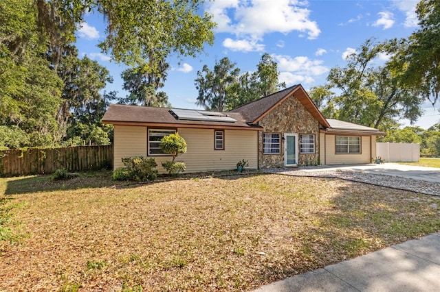 1240 W Voorhis Ave, Deland, FL 32720 - ranch-style house with fence, solar panels, a front yard, and stone siding