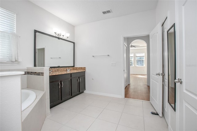 bathroom featuring tile patterned flooring, vanity, tiled bath, and a textured ceiling