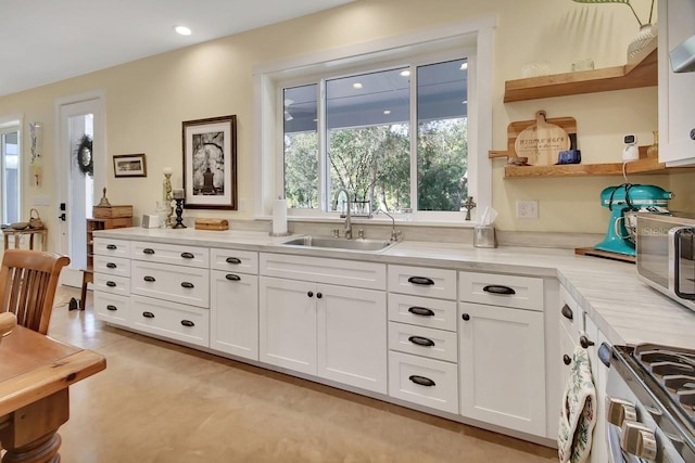 kitchen featuring white cabinetry, sink, and stainless steel range