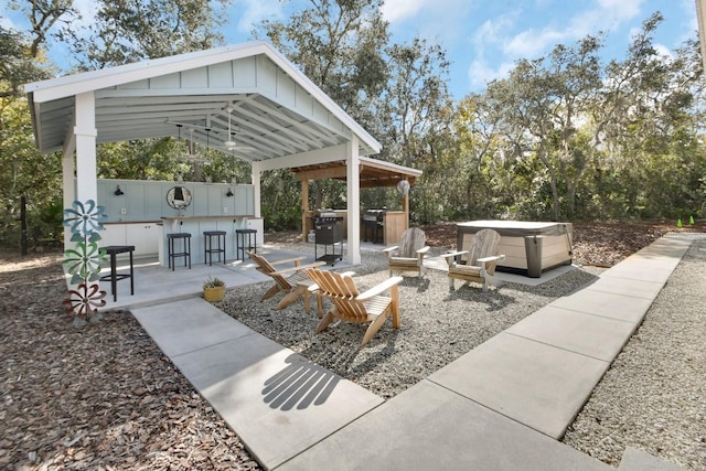 view of patio featuring a hot tub, a gazebo, and exterior bar