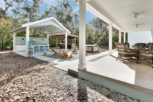 view of patio / terrace featuring exterior bar, ceiling fan, and a hot tub