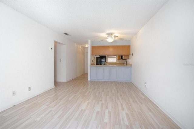 unfurnished living room featuring ceiling fan, light hardwood / wood-style floors, and a textured ceiling