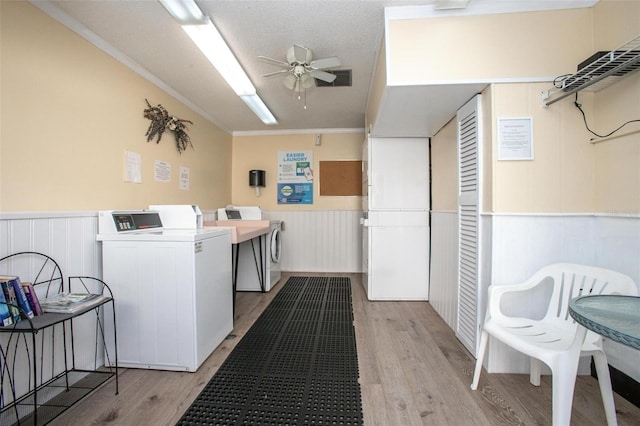 clothes washing area with ceiling fan, ornamental molding, a textured ceiling, separate washer and dryer, and light wood-type flooring