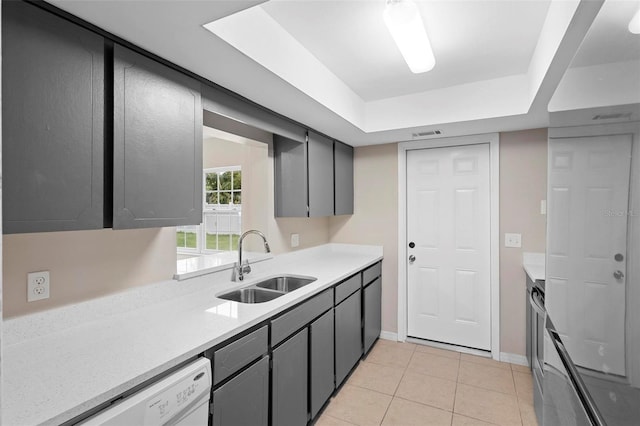 kitchen featuring sink, light tile patterned floors, gray cabinets, white dishwasher, and a raised ceiling