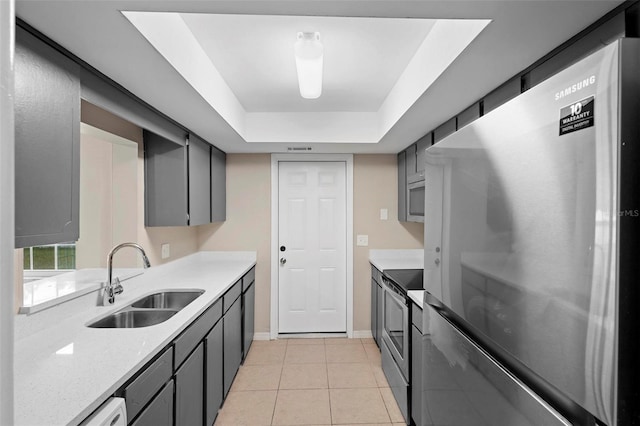 kitchen featuring sink, light tile patterned floors, gray cabinetry, stainless steel appliances, and a tray ceiling