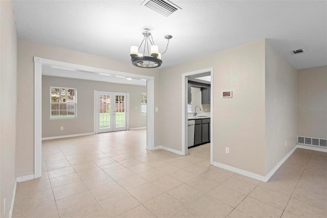 interior space with sink, light tile patterned floors, an inviting chandelier, and french doors