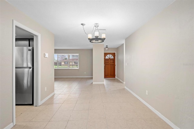 tiled foyer featuring an inviting chandelier and a textured ceiling