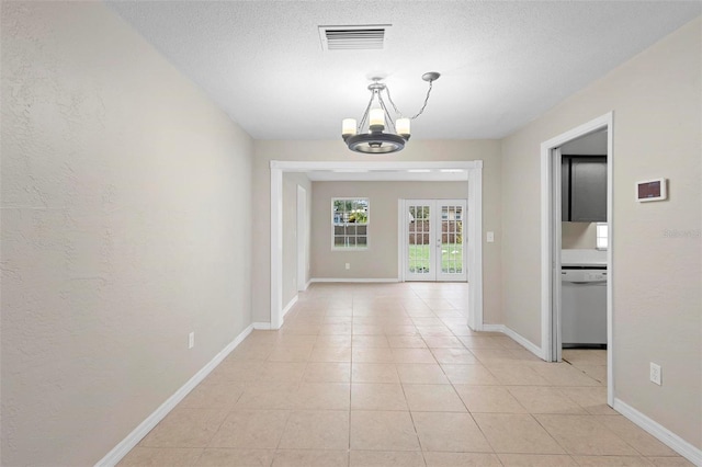 hall featuring an inviting chandelier, french doors, and light tile patterned floors