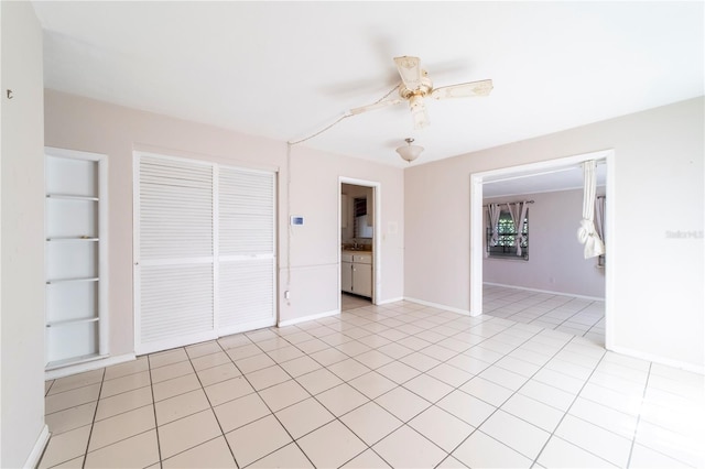 tiled empty room featuring ceiling fan and built in shelves