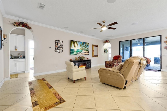 tiled living room with ceiling fan, ornamental molding, and a textured ceiling