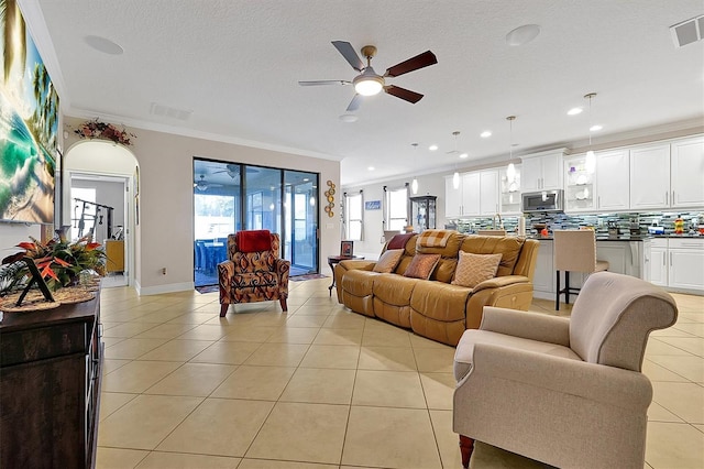 tiled living room with crown molding, a textured ceiling, and ceiling fan