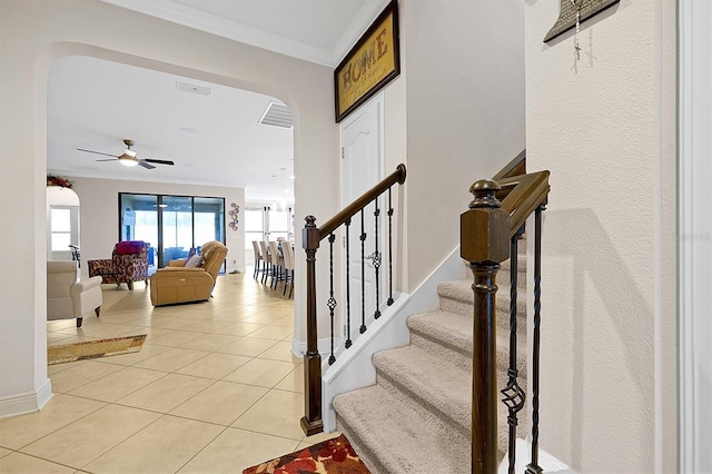 stairs featuring ceiling fan, ornamental molding, and tile patterned flooring