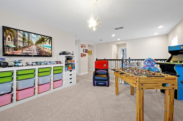 recreation room featuring light carpet and a textured ceiling