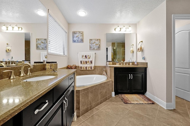 bathroom with vanity, tile patterned flooring, a textured ceiling, and tiled tub