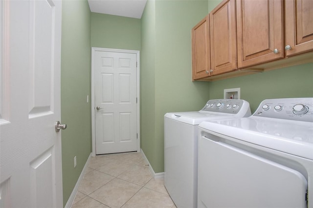 washroom featuring cabinets, washing machine and dryer, and light tile patterned floors