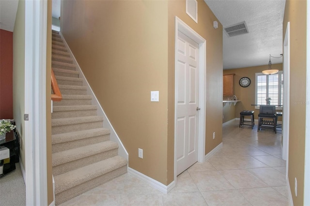 staircase with tile patterned floors and a textured ceiling