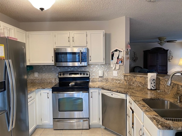 kitchen with light tile patterned flooring, appliances with stainless steel finishes, white cabinetry, sink, and a textured ceiling