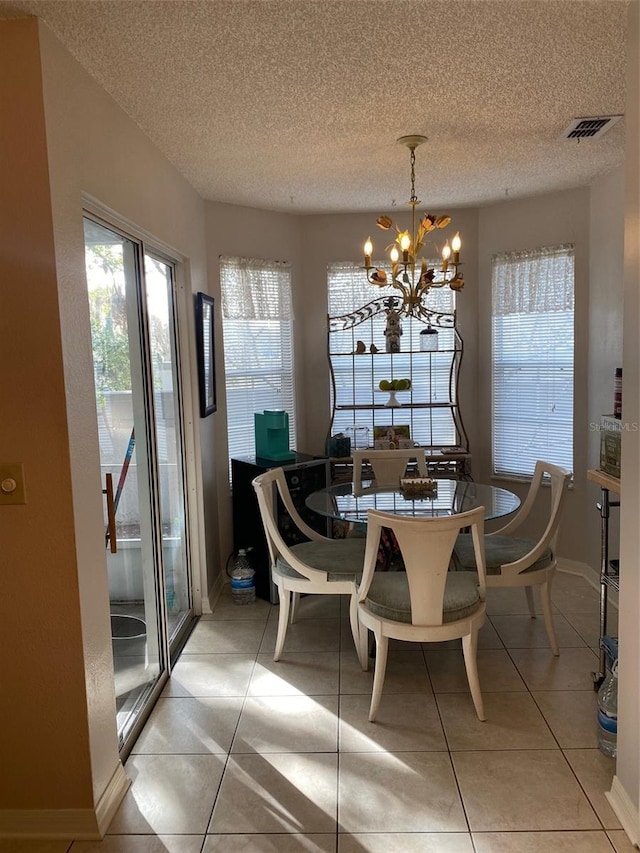 dining space with light tile patterned floors, a textured ceiling, and a notable chandelier