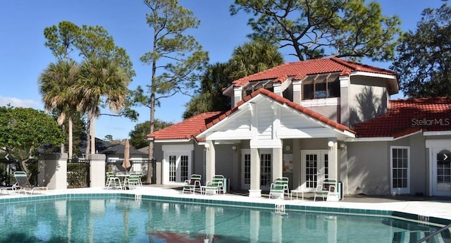 back of property featuring french doors, a fenced in pool, and a patio area