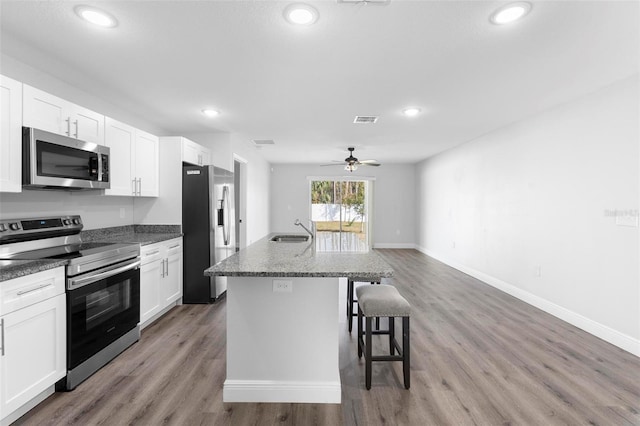 kitchen featuring stainless steel appliances, sink, a center island with sink, and white cabinets