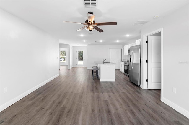 kitchen with white cabinetry, sink, a breakfast bar area, stainless steel appliances, and a center island with sink