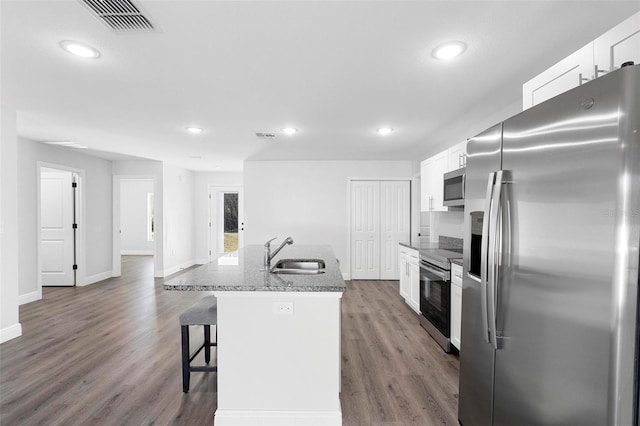 kitchen with sink, dark wood-type flooring, white cabinetry, stainless steel appliances, and an island with sink