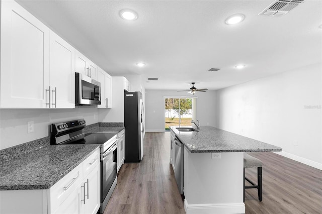 kitchen featuring stainless steel appliances, sink, a kitchen island with sink, and white cabinets