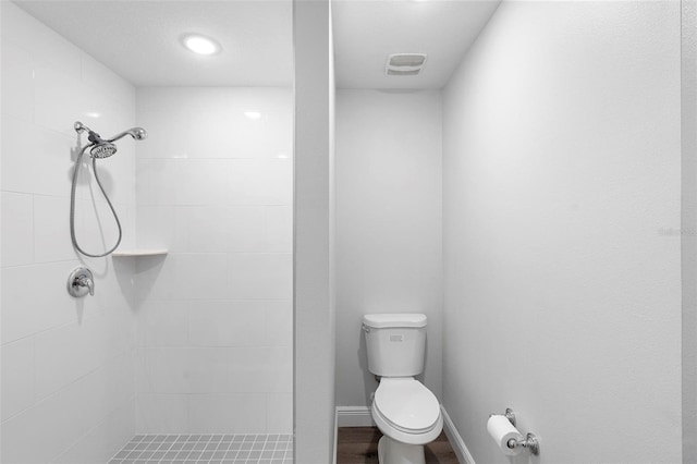 bathroom with a tile shower and toilet