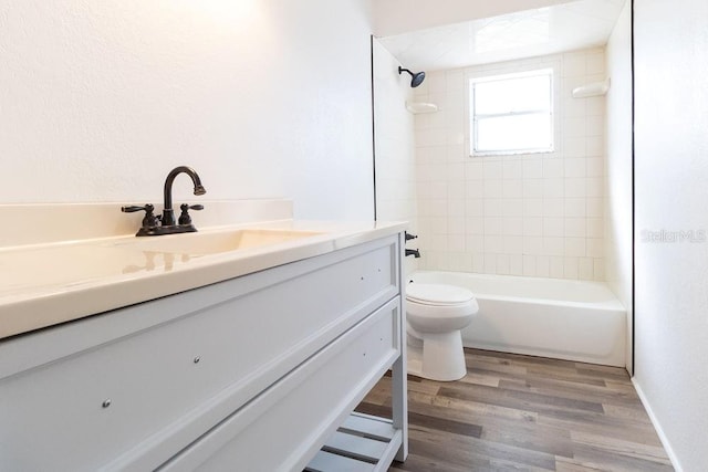 full bathroom featuring vanity, hardwood / wood-style floors, tiled shower / bath combo, and toilet