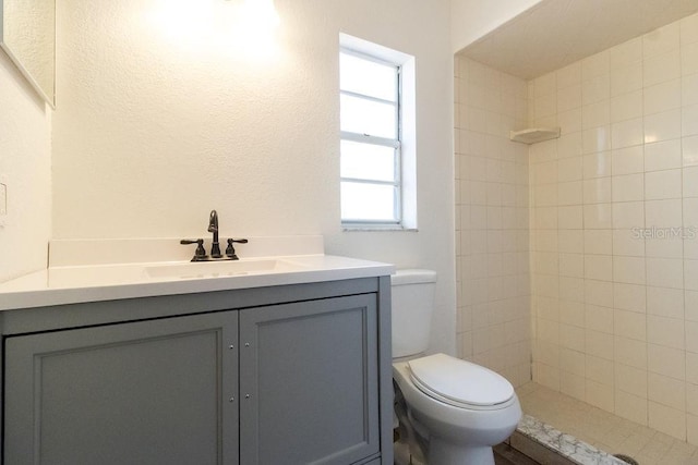 bathroom featuring vanity, toilet, and a tile shower