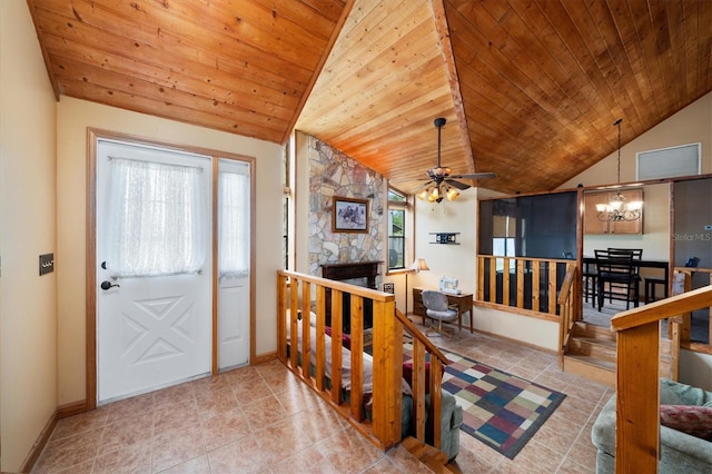 foyer entrance with wood ceiling, a stone fireplace, vaulted ceiling, and a notable chandelier