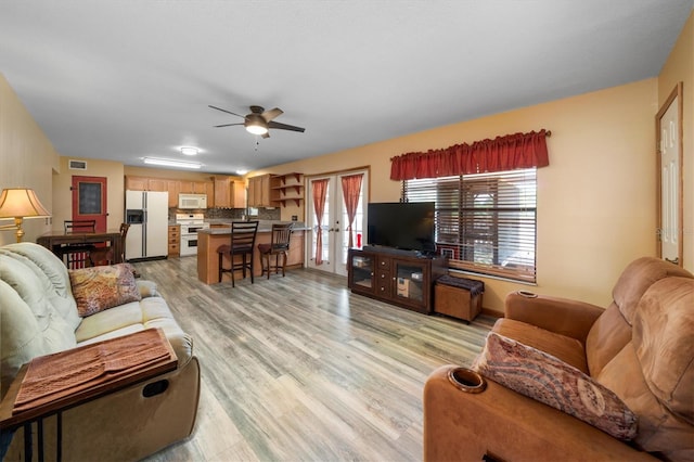 living room featuring ceiling fan, light wood-type flooring, and french doors