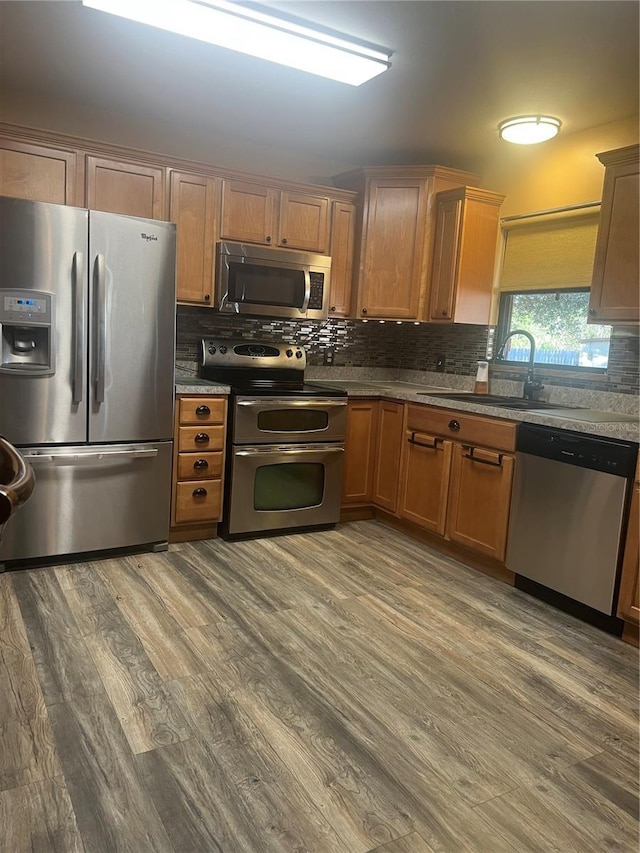 kitchen with hardwood / wood-style flooring, stainless steel appliances, sink, and tasteful backsplash