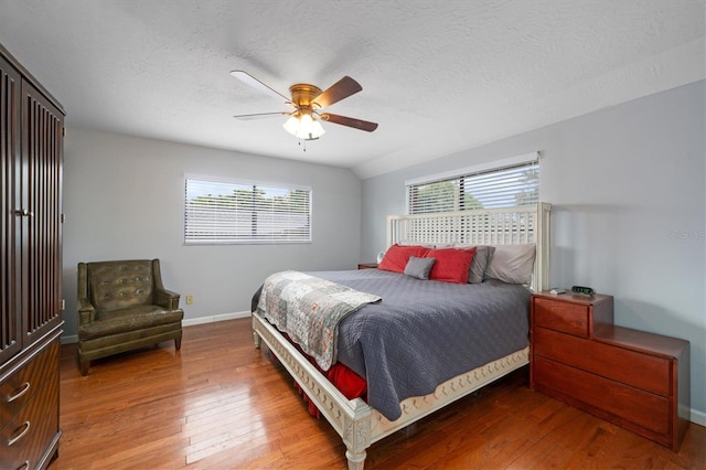 bedroom with hardwood / wood-style flooring, ceiling fan, lofted ceiling, and a textured ceiling