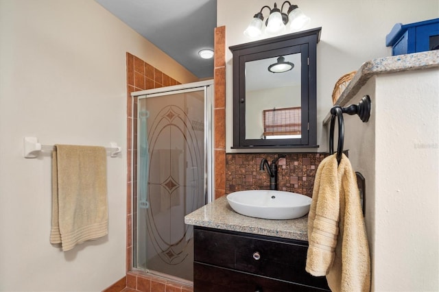 bathroom featuring tasteful backsplash, vanity, and a shower with door