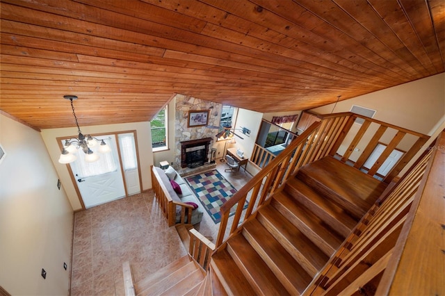 interior space featuring a notable chandelier, lofted ceiling, wooden ceiling, and a stone fireplace